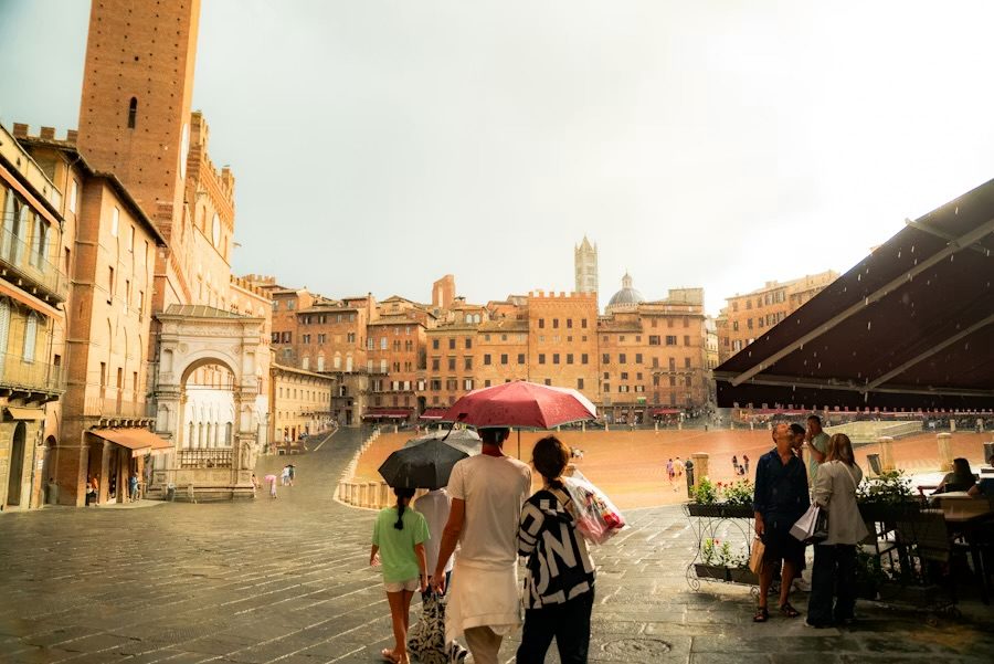 Die Piazza del Campo in Siena mit dem Torre del Mangia und Passanten